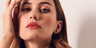 Mujer aplicando el lápiz labial como rubor para crear un estilo de maquillaje monocromático rosa