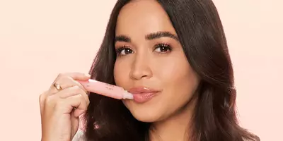 Mujer aplicando brillo labial en tubos jugosos.