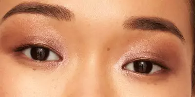 Primer plano de una glamorosa sombra de ojos en tono oro rosa sobre ojos marrones con monolípidos