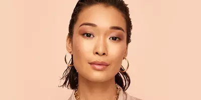 Estilo de maquillaje de almejas en tono oro rosa con brillo y rubor para labios de sombra de ojos en un modelo con tono de piel medio