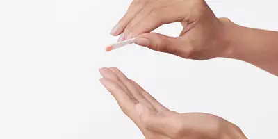 Manos con una cantidad del tamaño de un guisante de imprimador facial en una espátula