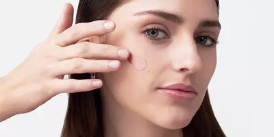 Mujer con piel texturizada y poros grandes aplicando imprimador facial borroso