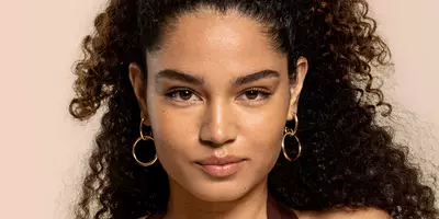 Mujer con una base de maquillaje natural brillante con base brillante y corrector de suero