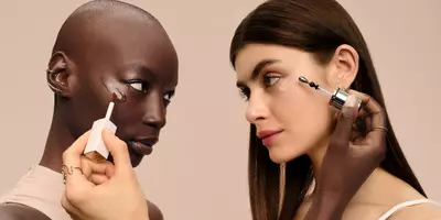 Dos mujeres aplicándose corrector debajo de los ojos y suero iluminador para ocultar e iluminar los círculos oscuros