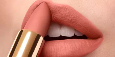 Mujer aplicando color del labial rosa suave con un lápiz labial natural