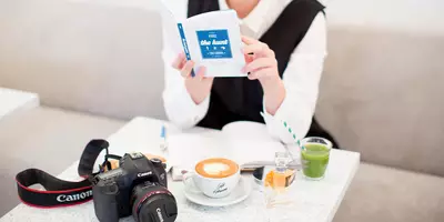 Mujer estudiando un libro sobre cómo maquillarse para obtener buenas imágenes y selfies.