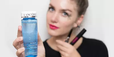 Mujer mostrando cómo quitarse el maquillaje de Halloween y la máscara de pestañas a prueba de agua con un removedor de maquillaje para ojos.