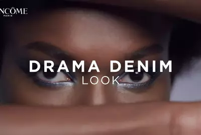 Mujer mostrando cómo crear un estilo de maquillaje y sombra para ojos inspirado en drama denim sobre piel oscura.